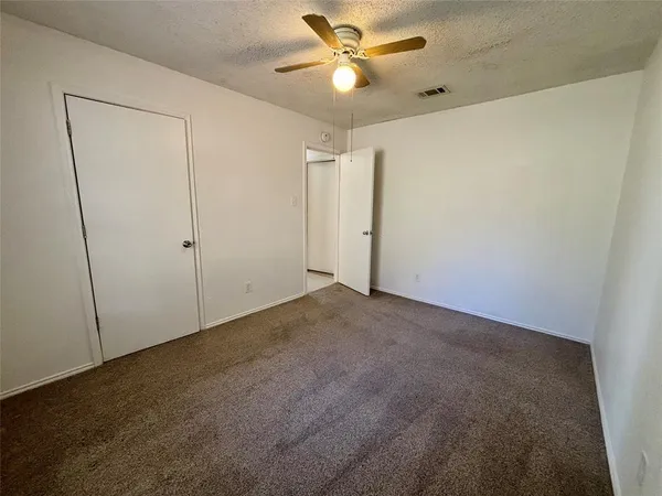 an empty room with a window and a fan