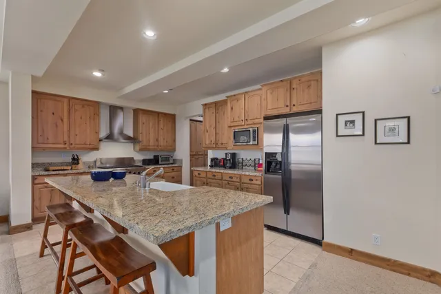 a kitchen with granite countertop a refrigerator and a stove top oven