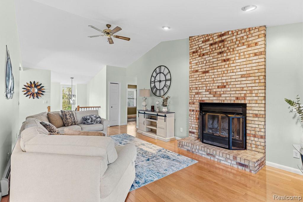 8742 Hyne Road Brighton, MI 48114 - Photo 13 of 65 Living area featuring light wood finished floors, ceiling fan, a fireplace, and lofted ceiling