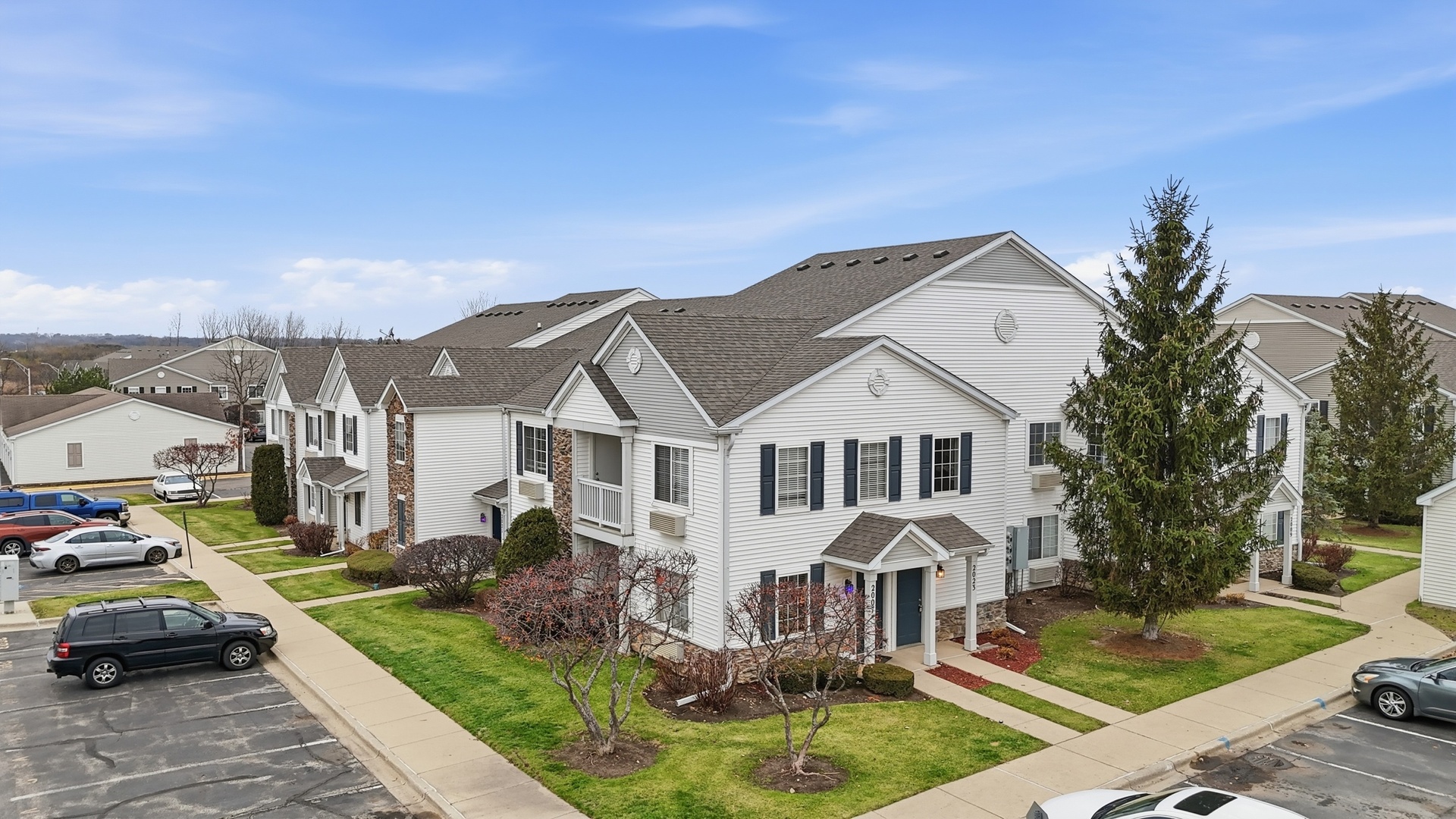 a front view of residential houses with yard and car parked