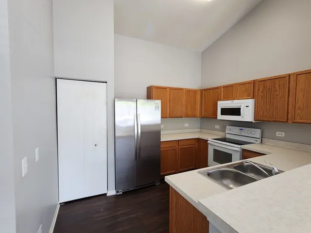 a kitchen with granite countertop a refrigerator and a stove top oven