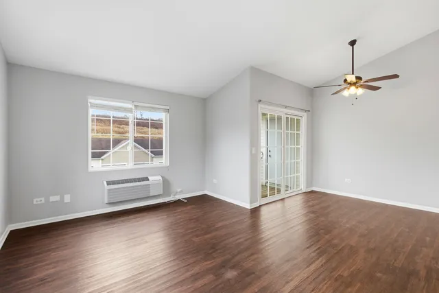 an empty room with wooden floor cabinet and windows