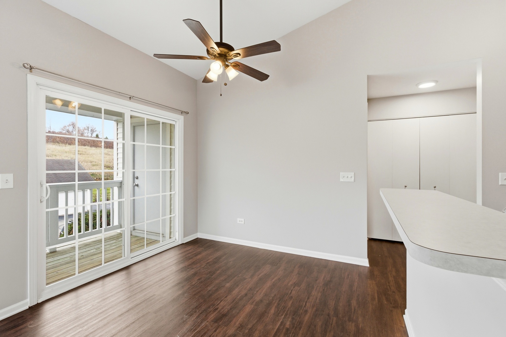 2023 Silverstone Drive, Unit 2023 Carpentersville, IL 60110 - Photo 7 of 19 an empty room with wooden floor cabinet and a view of kitchen