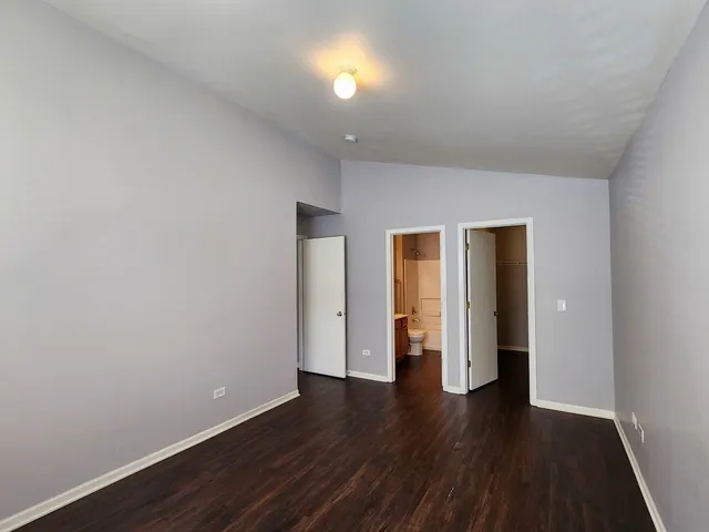 a view of an empty room with wooden floor and closet