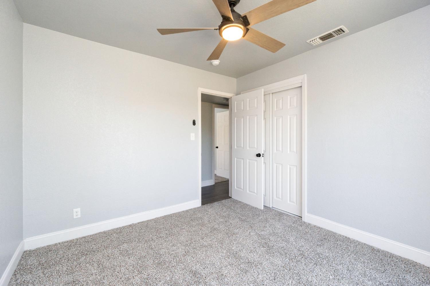 3086 West Hampton Way Fresno, CA 93722 - Photo 22 of 33 an empty room with a ceiling fan and a window