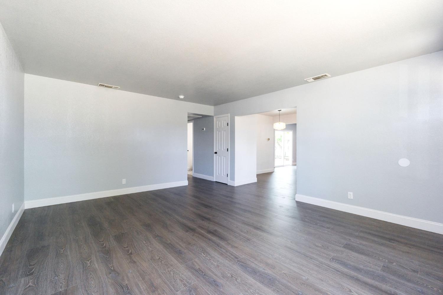 3086 West Hampton Way Fresno, CA 93722 - Photo 8 of 33 a view of an empty room with wooden floor and windows