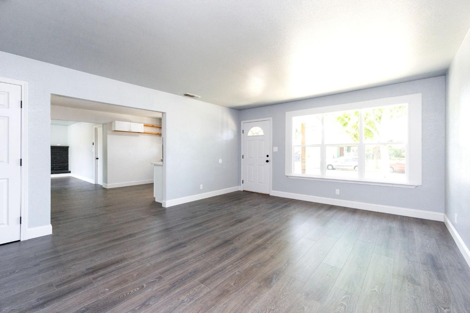 3086 West Hampton Way Fresno, CA 93722 - Photo 9 of 33 an empty room with wooden floor and windows