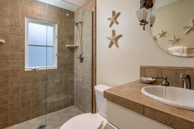 a bathroom with a granite countertop sink a toilet and shower