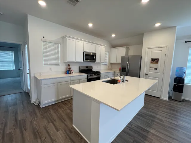 a kitchen that has a lot of white cabinets and stainless steel appliances