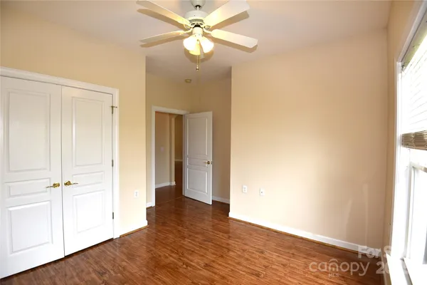 an empty room with wooden floor closet and windows