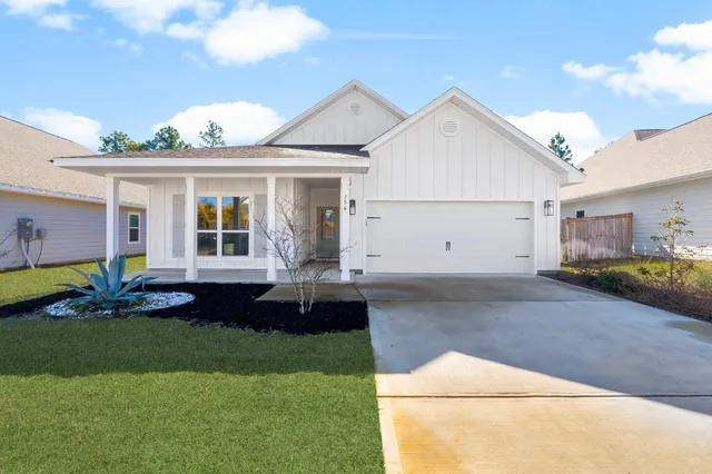 a view of a white house with a big yard and potted plants