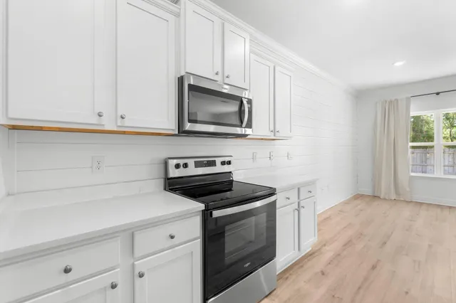 a kitchen with white cabinets and stainless steel appliances