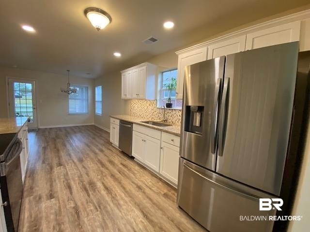 22713 Respite Lane Foley, AL 36535 - Photo 7 of 35 Kitchen with white cabinets, appliances with stainless steel finishes, light hardwood / wood-style floors, and backsplash