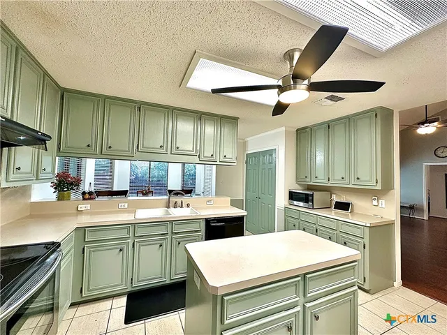an empty room with windows and chandelier fan