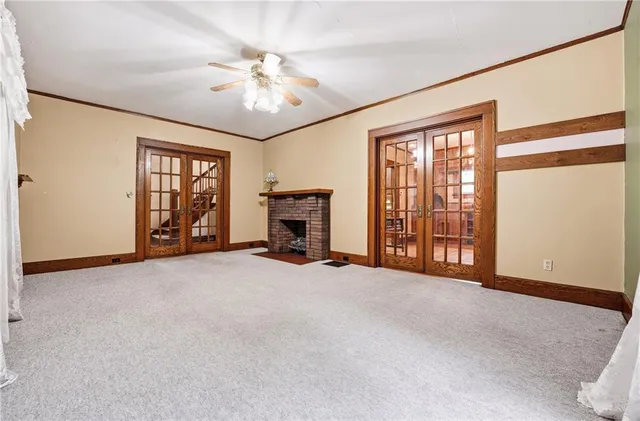 an empty room with chandelier fan and windows