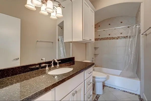 a bathroom with a granite countertop sink a toilet and shower