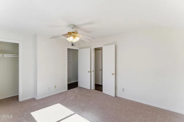 an empty room with wooden floor a ceiling fan and windows