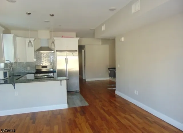 a kitchen with granite countertop a refrigerator and a stove top oven