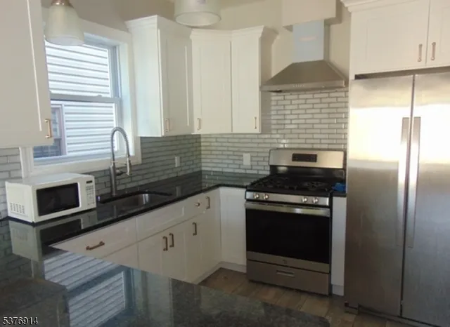 a kitchen with granite countertop a stove sink and refrigerator