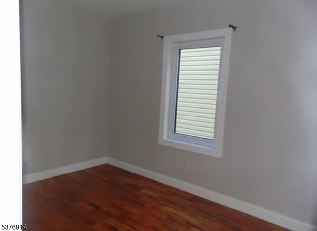 an empty room with wooden floor and a window