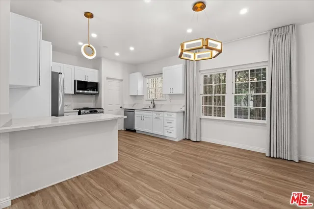 a large kitchen with stainless steel appliances granite countertop a stove and a wooden floors