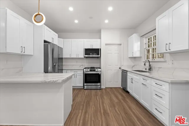 a kitchen with granite countertop a stove top oven a sink dishwasher and a refrigerator with wooden floor