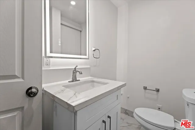a bathroom with a granite countertop toilet sink and mirror
