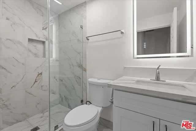 a bathroom with a granite countertop sink toilet a mirror and shower