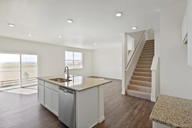 a kitchen that has a sink a stove and wooden floor