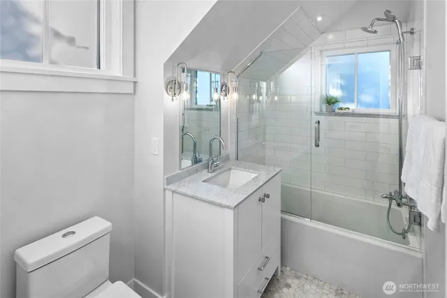 a bathroom with a granite countertop sink a toilet and shower