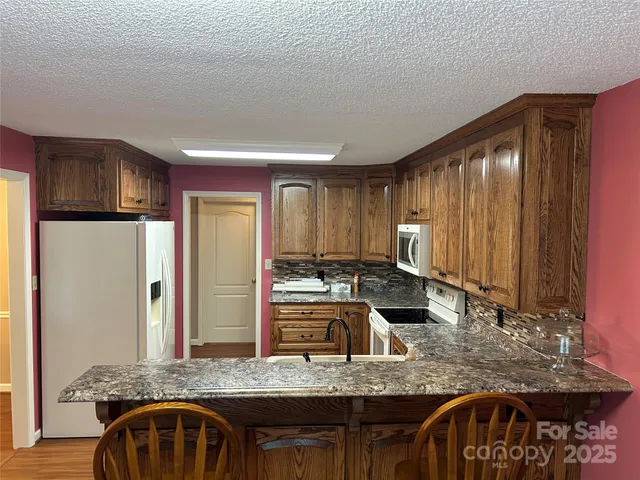 a kitchen with granite countertop a sink a counter top space and stainless steel appliances
