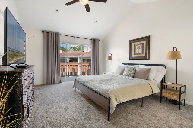 a spacious bedroom with a bed and a flat tv screen