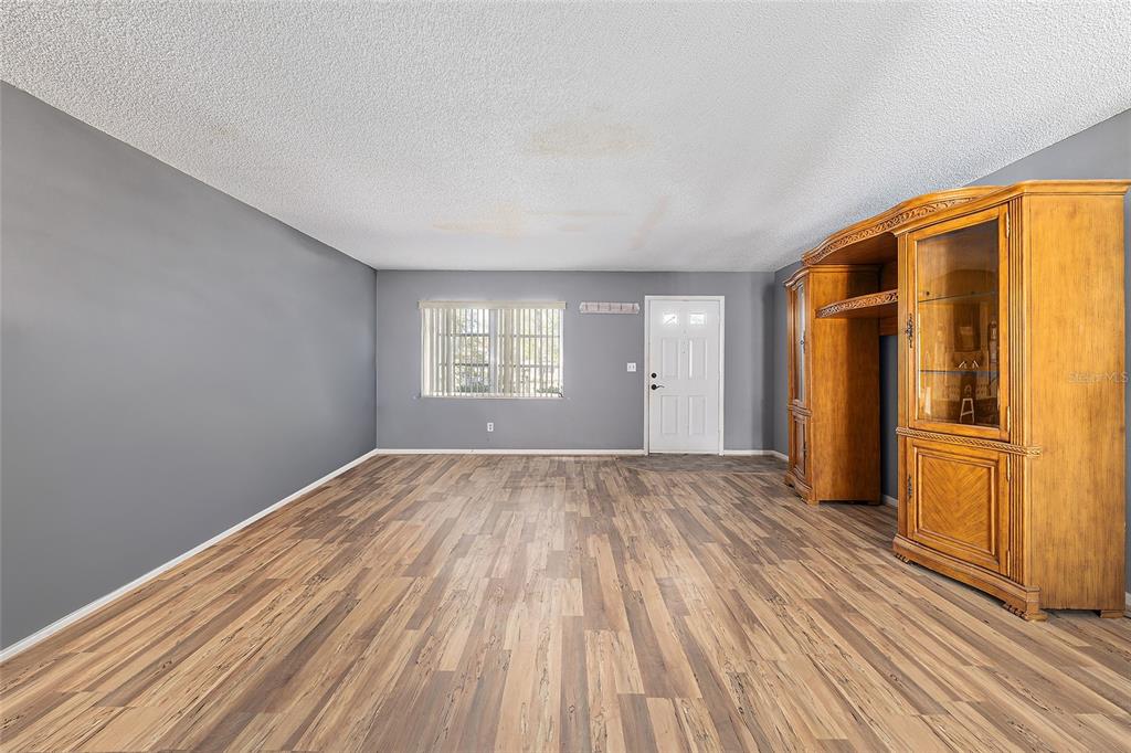 9951 Southwest 88th Court Road, Unit C Ocala, FL 34481 - Photo 5 of 46 an empty room with wooden floor kitchen view and windows