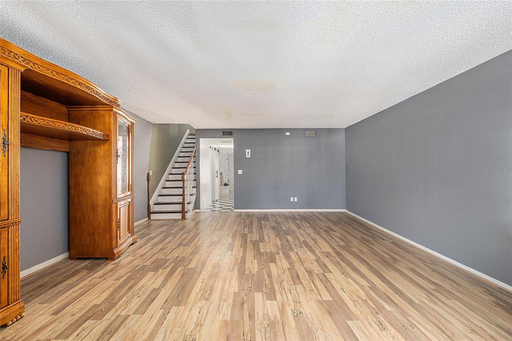 9951 Southwest 88th Court Road, Unit C Ocala, FL 34481 - Photo 6 of 46 an empty room with wooden floor and stairs