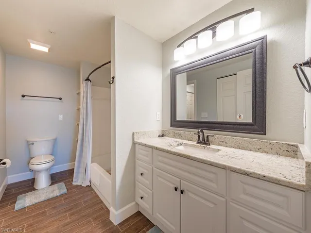 a bathroom with a granite countertop toilet sink and a mirror