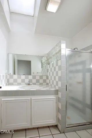 a bathroom with a granite countertop sink a mirror and shower