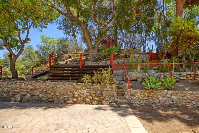 a view of a barn with wooden fence and a large tree