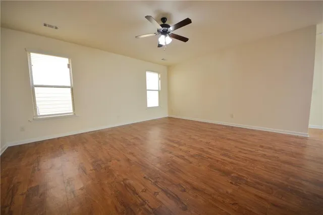 a view of an empty room with window and wooden floor