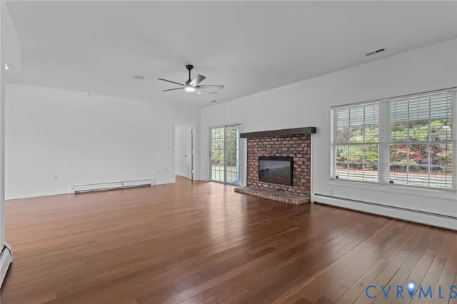 an empty room with wooden floor fireplace and windows
