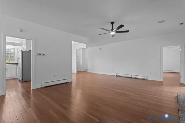 an empty room with wooden floor and ceiling fan