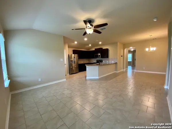 a view of a living room a ceiling fan and kitchen view