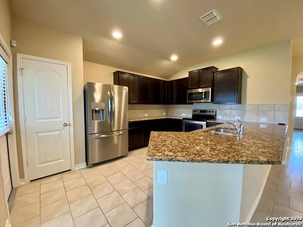 a kitchen with stainless steel appliances granite countertop a refrigerator and a sink