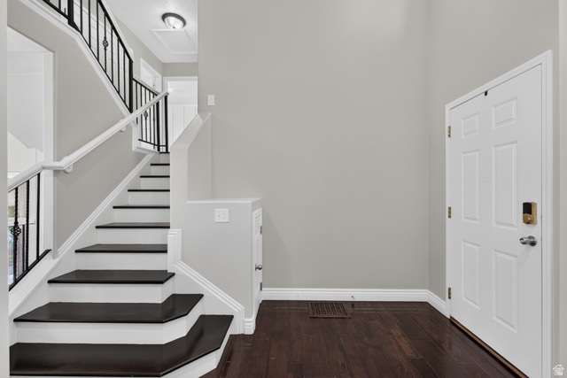 2223 North Pointe Meadow Loop Lehi, UT 84048 - Photo 7 of 56 Two-story entryway featuring wood-finish flooring, a white paneled door, and a staircase with white risers and dark treads, complemented by a black wrought iron railing and white handrail