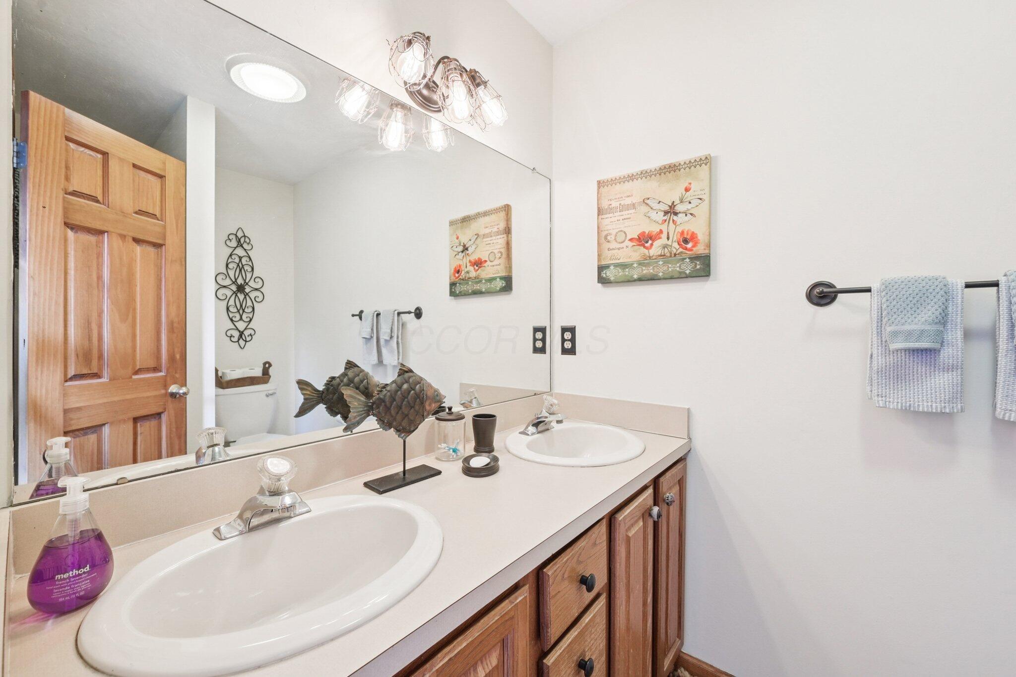 7700 Plumb Road Galena, OH 43021 - Photo 74 of 94 Upper level full bath with double sinks, wall-to-wall mirror, and updated lighting—perfect for shared use.