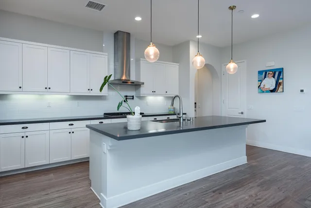 a kitchen with stainless steel appliances granite countertop a sink a stove and a wooden floors