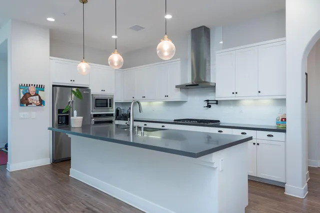 a kitchen with stainless steel appliances granite countertop a sink a stove and a wooden floors