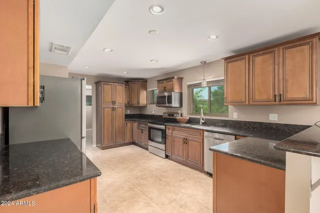 a kitchen with stainless steel appliances granite countertop a stove a sink and a refrigerator