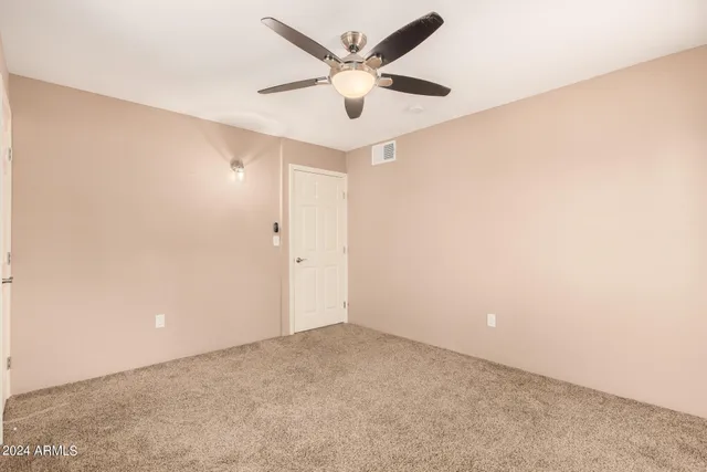 an empty room with closet and ceiling fan