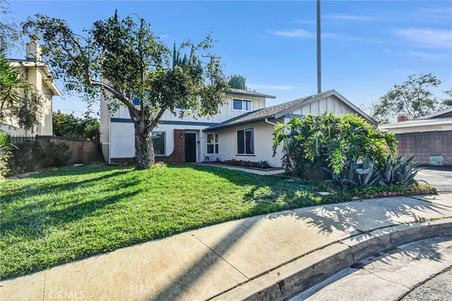 a front view of a house with a yard and potted plants