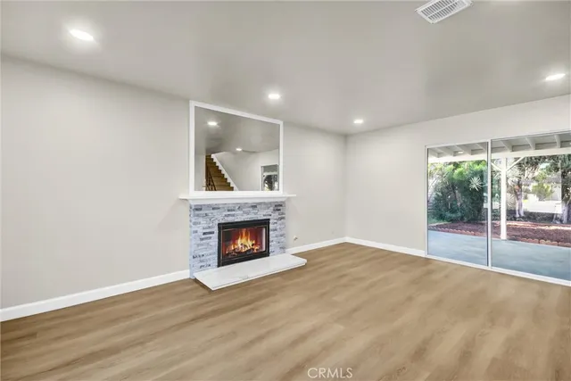 a view of an empty room with wooden floor and a fireplace